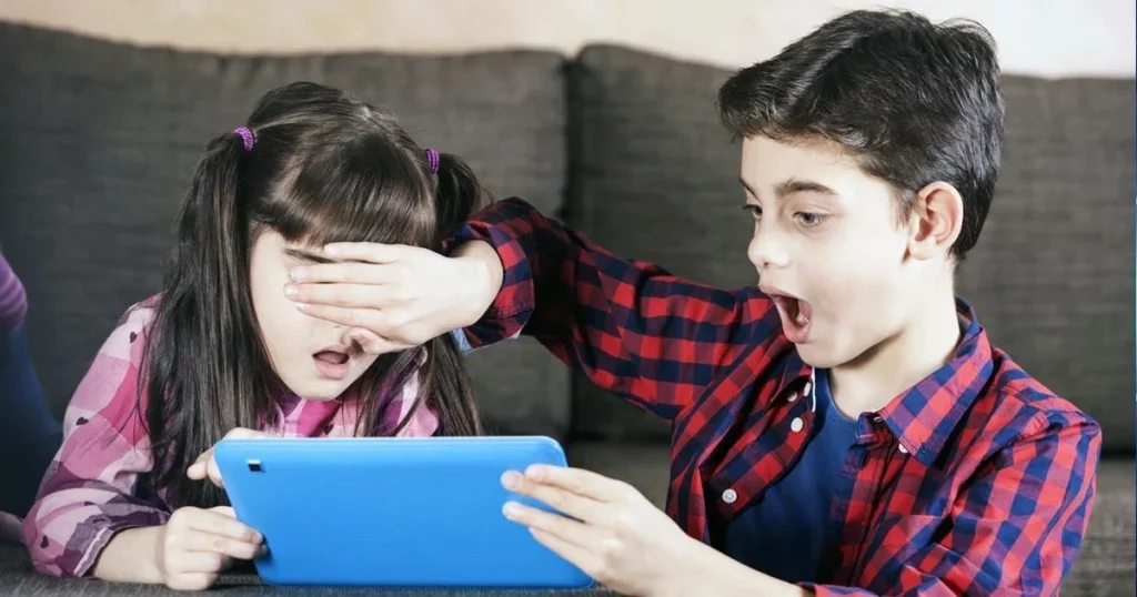 A young girl covers her eyes with her hand, looking upset, while a boy next to her expresses shock at what they see on the tablet, highlighting the need for discussions on cyberethics for our kids.