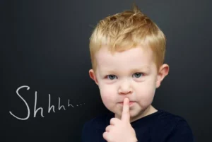 A child holding a finger to their lips symbolizes a secret in their online activities